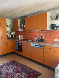 a kitchen with orange cabinets and a sink at Ferienwohnung Meusburger in Hittisau +7 photos