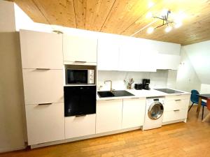 a kitchen with white cabinets and a washing machine at Beau Duplex Gravelines centre in Gravelines