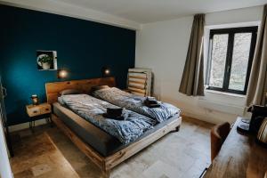 ein Schlafzimmer mit einem Bett und einer blauen Wand in der Unterkunft Maison Ubuntu in Froidfontaine