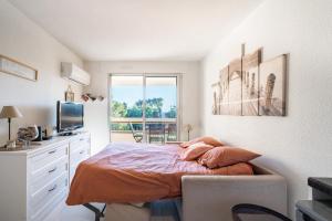 a bedroom with a bed and a desk and a television at Edenesterel in Saint-Raphaël