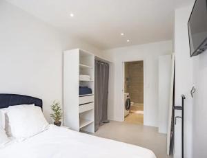 a white bedroom with a bed and a bathroom at Le Troyal - hypercentre et confort in Troyes