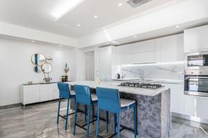 a kitchen with white cabinets and blue chairs at Luxury Penthouse Sea View with terrace in Giardini Naxos +43 photos