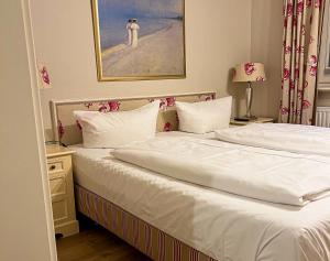 a bedroom with two beds and a painting on the wall at Landhaus auf der Düne, App 2 in Rantum