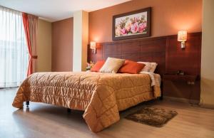 ein Schlafzimmer mit einem großen Bett mit hölzernem Kopfteil in der Unterkunft Hotel Rosamia in Cuenca