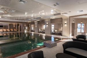 a swimming pool in a hotel with chairs and tables at TAOR Karpaty Resort & Spa in Skhidnitsa