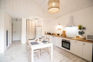 a kitchen with white cabinets and a table and chairs at Wooden lodge with garden in Vielle-Saint-Girons