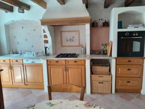 a kitchen with wooden cabinets and a stove top oven at Ravissante longère avec grand jardin et cheminée in Pellevoisin +16 photos