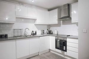 a white kitchen with white cabinets and a sink at Luxury 2 Bedroom Apartment near Stratford Station for Corporate and Group Stays in London