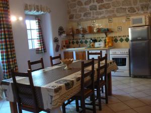 Una cocina con mesa y sillas y un refrigerador. en La Calade, en Rosières