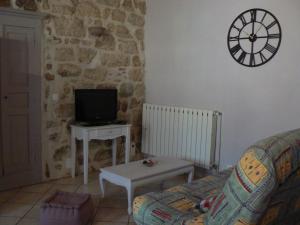 Una sala de estar con un sofá y un reloj en la pared. en La Calade, en Rosières