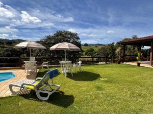 une cour avec des chaises et des parasols à côté d'une piscine dans l'établissement Chácara Verzani, à Socorro