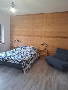 Un dormitorio con una cama y un sofá azul. en gîte l'œuf ou la poule, parking privé, sur domaine viticole, en Ribeauvillé