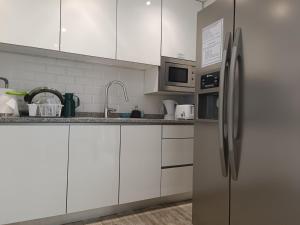 una cucina con armadi bianchi e frigorifero in acciaio inossidabile di Cachinnans Hostel & Apartments a Vila do Conde