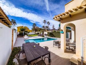 a patio with a wooden table and chairs next to a swimming pool at Beach Villa Playa Flamenca in Orihuela Costa