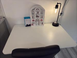 a white table with a lamp and a black chair at Crown's Court in Orpington