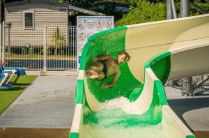 a boy riding a wave on a water slide at ZEcamping animé dog friendly familial piscine couverte in Saint-Georges-dʼOléron