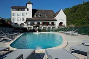 a hotel with a swimming pool in front of a building at Logis Hôtel restaurant La Rivière in Entraygues-sur-Truyère