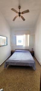 une chambre avec un lit et un ventilateur de plafond dans l'établissement Casa tipo Chalet a 50m de la Playa en SantaTeresita, à Santa Teresita