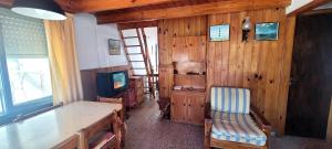 une pièce avec un mur en bois avec une table et une télévision dans l'établissement Casa tipo Chalet a 50m de la Playa en SantaTeresita, à Santa Teresita