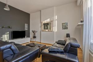 a living room with a leather couch and a tv at B&B Leopold & Appartementen in Sint-Truiden