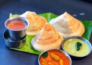 a green plate of food with bread and dipping sauces at Harikrishna Park in Coimbatore