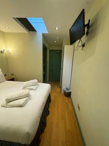 a room with two beds and a television on the wall at Matheson Olympia Hotel in London