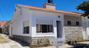 une maison en briques blanches avec une fenêtre dans l'établissement Casa tipo Chalet a 50m de la Playa en SantaTeresita, à Santa Teresita