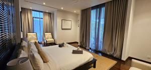 a bedroom with a bed and two chairs and windows at Villa Princess Stephanie in Kata Beach