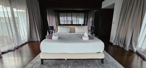 a large white bed in a room with windows at Villa Princess Stephanie in Kata Beach