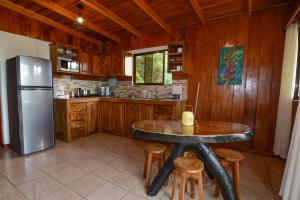 a kitchen with a table and a refrigerator at Las Marias Monteverde - Mountain View Cottages & Gardens in Monteverde Costa Rica