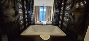 a bathroom with a bath tub in a room with windows at Villa Princess Stephanie in Kata Beach
