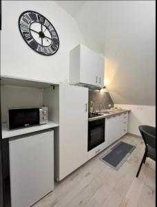 a kitchen with a large clock on the wall at Chtx-Style ancien - Fibre - Commerces - Transports in Châteauroux +5 photos