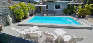 a swimming pool with white chairs and a table at Karon Homes in Karon Beach