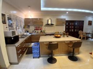 eine Küche mit Holzschränken und eine Insel mit Barhockern in der Unterkunft Appartement Villa Saran, Nongo in Conakry