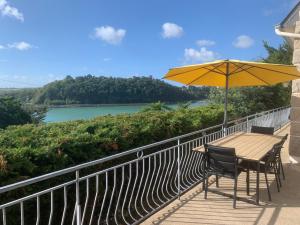 a table and chairs with an umbrella on a balcony at Maison vue mer baie de Saint Brieuc in Plérin