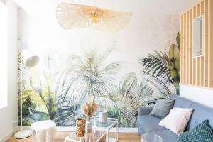 a living room with a blue couch and a mural of plants at Petit appartement pour 2 à 3 personnes in Caen
