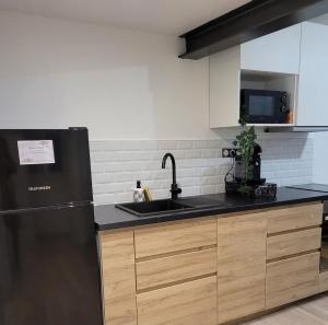 a kitchen with a black refrigerator and a sink at Appartement Moderne in Manosque
