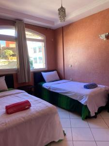 a bedroom with two beds and a window at Sunrise sea view apartment A17 in Tamraght Ou Fella +25 photos