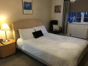a bedroom with a white bed with a black pillow on it at SleepNeat in Ascot