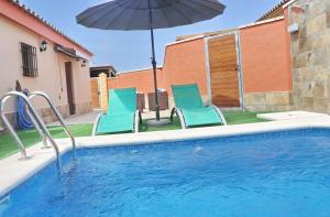 basen z dwoma krzesłami i parasolem w obiekcie Chalet Sultan con piscina w mieście Conil de la Frontera