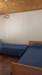 a bedroom with two beds with blue sheets and a ceiling at Cabañas del Valle in Huerta Grande
