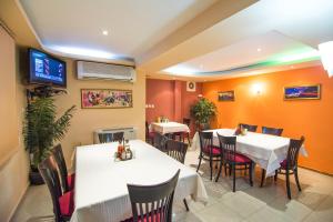 a dining room with tables and chairs and a tv at Family Hotel Victoria Gold in Mineralni Bani