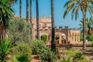 einen Garten mit Palmen und ein Gebäude in der Unterkunft Castell Villa Bohío Mallorca in Urbanicacion ses palmeres + 83 Fotos