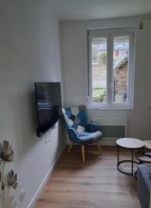 uma sala de estar com uma cadeira azul e uma televisão em Gite Ardennais 18 personnes "les gronchons" em Haybes