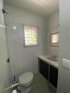 a white bathroom with a toilet and a sink at Sobrado Veneza Caiobá 2 Quartos in Matinhos