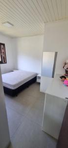 a room with a bed and a white wall at stone house in Balneário Gaivotas