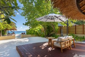 Un patio con una mesa y sillas y una sombrilla. en Banyan Tree Vabbinfaru, en Male