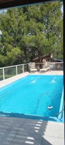 a blue swimming pool with two chairs and a tree at Ollagua casa con pileta Villa Ventana in Villa Ventana