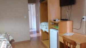 a small room with a desk and a bed and a table and a deskablish at Estrelatto Residence in Gramado