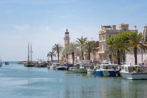 a group of boats docked in a harbor with a clock tower at AS21755 - Grand P3 Vue Canal au cœur du Centre-Ville à 20m de la plage in Le Grau-du-Roi